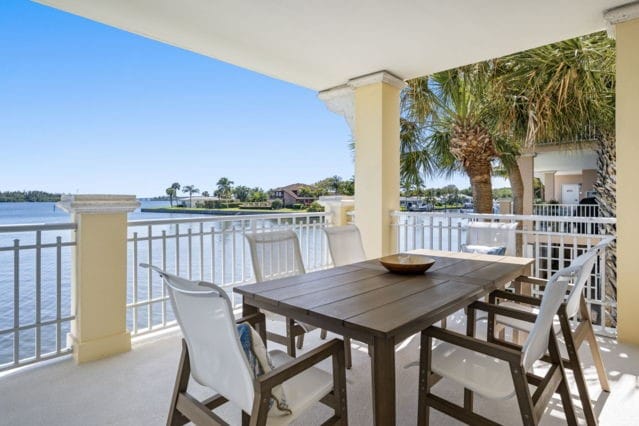 view of patio with a balcony, outdoor dining area, and a water view