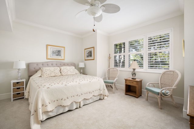 carpeted bedroom featuring ceiling fan, crown molding, and baseboards