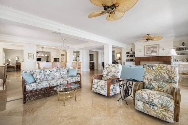 living room featuring crown molding, built in features, a ceiling fan, and a tray ceiling