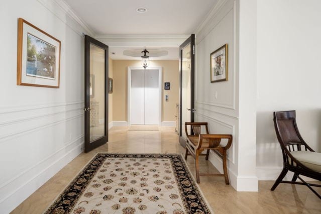 corridor with baseboards, elevator, crown molding, and a decorative wall