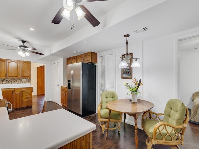 kitchen with stainless steel refrigerator with ice dispenser, pendant lighting, ceiling fan, and decorative backsplash