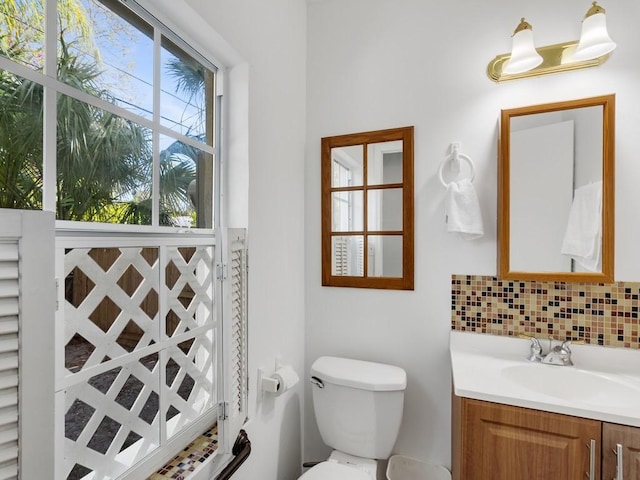 bathroom with vanity, toilet, and decorative backsplash