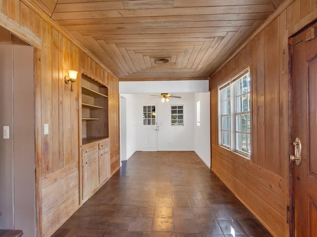 corridor featuring wood ceiling, ornamental molding, wooden walls, and built in shelves