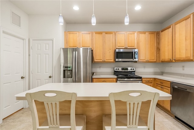 kitchen featuring stainless steel appliances, a kitchen bar, hanging light fixtures, and a kitchen island