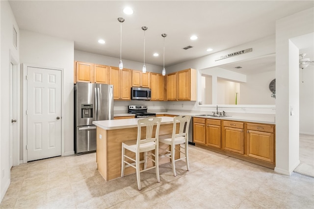 kitchen featuring sink, a kitchen island, a breakfast bar, appliances with stainless steel finishes, and decorative light fixtures