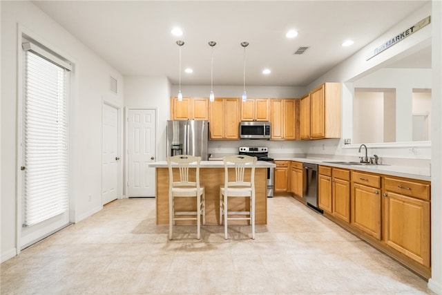 kitchen with a kitchen island, appliances with stainless steel finishes, decorative light fixtures, a kitchen bar, and sink