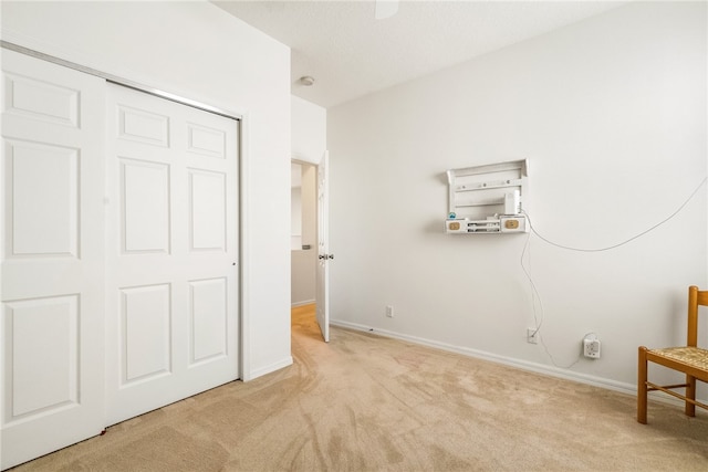 unfurnished bedroom with light colored carpet and a closet