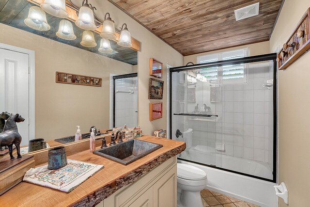 full bathroom featuring toilet, wood ceiling, tile patterned flooring, combined bath / shower with glass door, and vanity