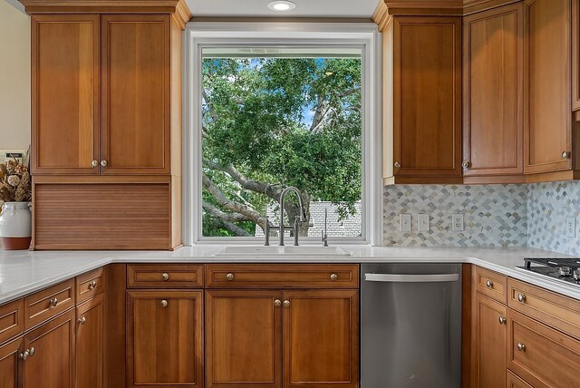 kitchen with stainless steel dishwasher, a healthy amount of sunlight, sink, and backsplash