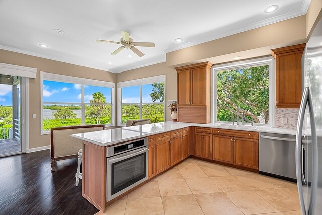 kitchen with kitchen peninsula, appliances with stainless steel finishes, and a healthy amount of sunlight