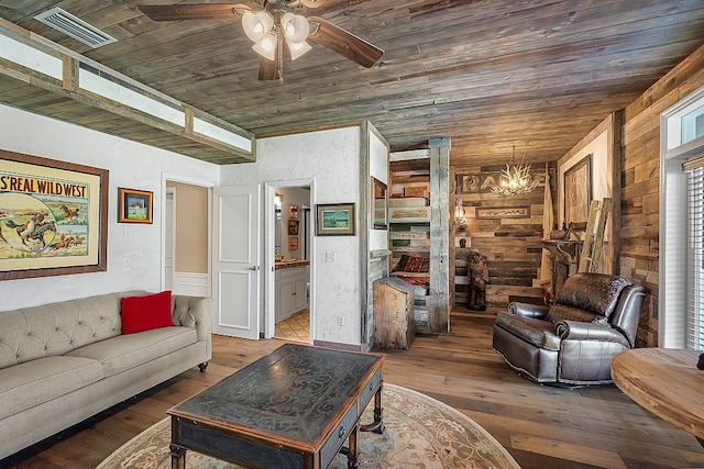 living room featuring hardwood / wood-style floors, ceiling fan with notable chandelier, wooden walls, and wood ceiling