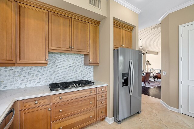 kitchen with crown molding, appliances with stainless steel finishes, light tile patterned floors, light stone countertops, and decorative backsplash