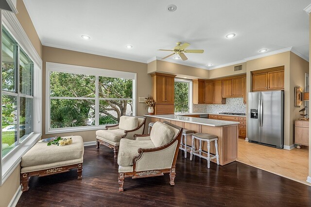 kitchen featuring ornamental molding, stainless steel appliances, a kitchen island, backsplash, and dark hardwood / wood-style floors