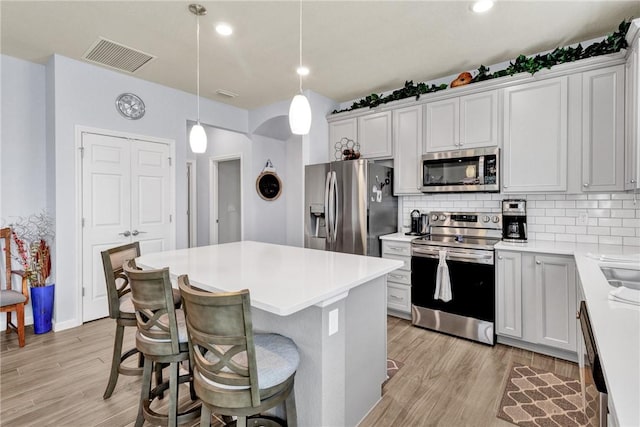 kitchen featuring pendant lighting, stainless steel appliances, a breakfast bar, and white cabinets