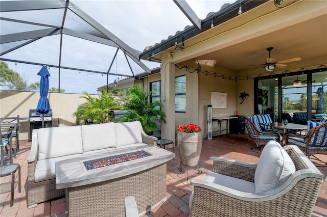 view of patio with grilling area, an outdoor living space with a fire pit, ceiling fan, and glass enclosure