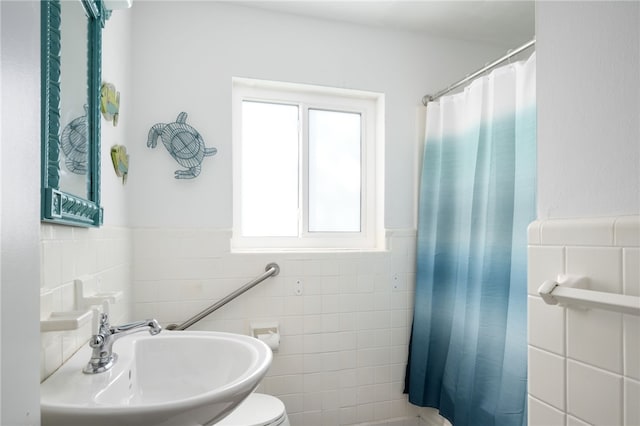 bathroom with a shower with shower curtain, toilet, tile walls, and sink