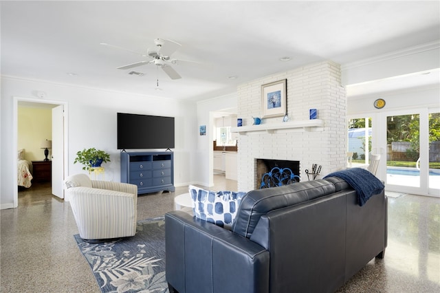 living room with a brick fireplace, ceiling fan, and crown molding