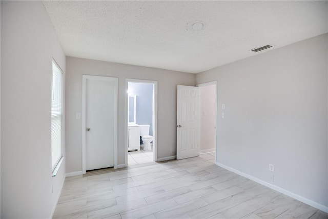 spare room with baseboards, visible vents, and a textured ceiling