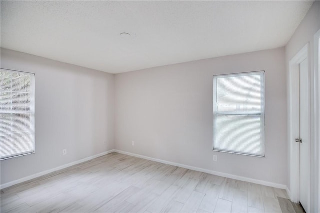 unfurnished room with light wood finished floors and baseboards