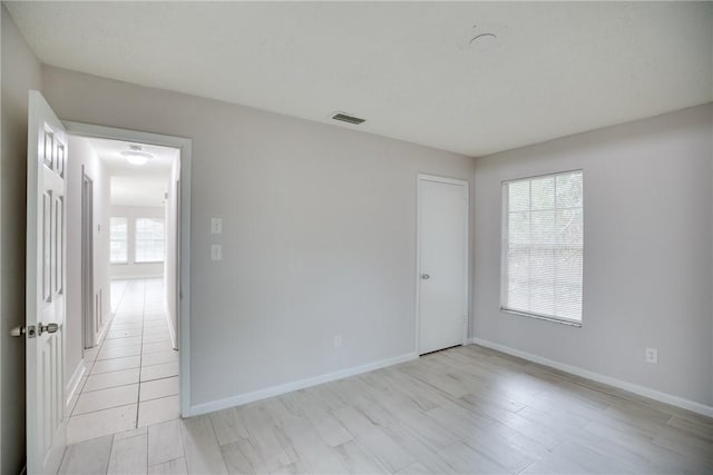 unfurnished room with light wood finished floors, baseboards, and visible vents