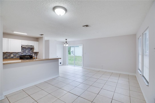 kitchen featuring tasteful backsplash, visible vents, white cabinets, light countertops, and black range oven