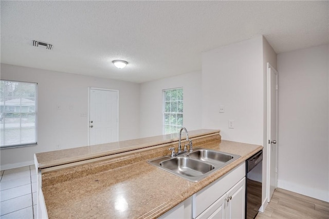 kitchen with a textured ceiling, a sink, visible vents, white cabinetry, and black dishwasher