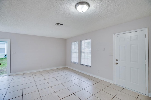 spare room featuring visible vents, a textured ceiling, baseboards, and light tile patterned floors