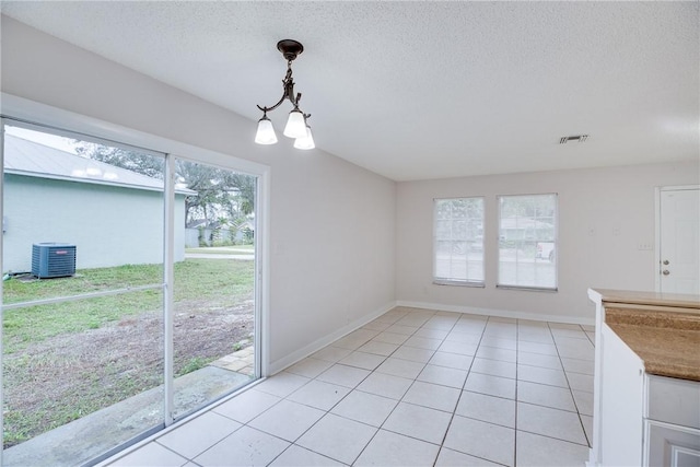 unfurnished dining area featuring a notable chandelier, light tile patterned floors, visible vents, a textured ceiling, and baseboards