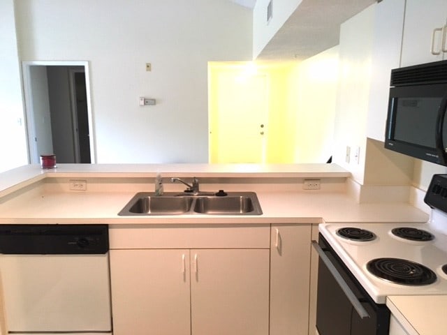 kitchen featuring white cabinetry, sink, and white appliances