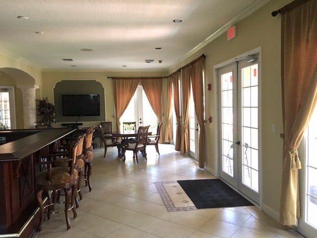 dining area featuring french doors, a healthy amount of sunlight, crown molding, and light tile patterned floors