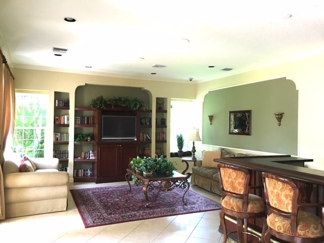 living room featuring light tile patterned floors and crown molding