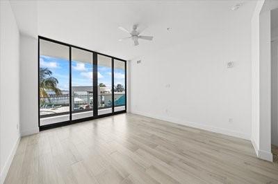 225 Strand Dr Unit 204, Melbourne Beach, FL 32951 - spare room with light wood-type flooring, a ceiling fan, and a wall of windows