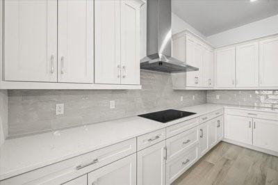 225 Strand Dr Unit 204, Melbourne Beach, FL 32951 - kitchen featuring wall chimney range hood, black electric stovetop, light countertops, white cabinetry, and light wood-style floors