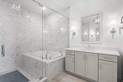 225 Strand Dr Unit 204, Melbourne Beach, FL 32951 - bathroom featuring vanity, a bath, a marble finish shower, and wood finished floors