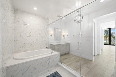 225 Strand Dr Unit 204, Melbourne Beach, FL 32951 - bathroom featuring a garden tub, vanity, and a marble finish shower