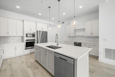 225 Strand Dr Unit 204, Melbourne Beach, FL 32951 - kitchen featuring appliances with stainless steel finishes, light wood-style flooring, light countertops, a kitchen island with sink, and recessed lighting