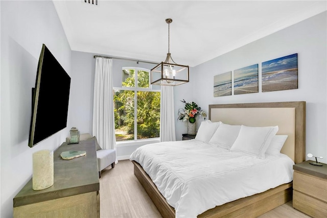 bedroom featuring an inviting chandelier, wood finished floors, visible vents, and baseboards
