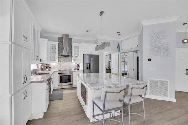 1255 Winding Oaks Cir E Unit 604, Vero Beach, FL 32963 - kitchen with appliances with stainless steel finishes, wall chimney exhaust hood, a kitchen island, decorative backsplash, and white cabinetry