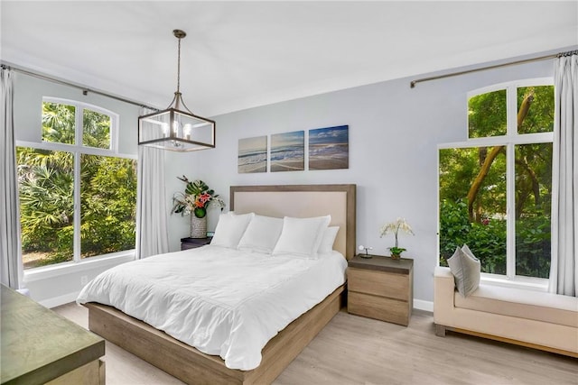 bedroom with wood finished floors, a notable chandelier, and multiple windows
