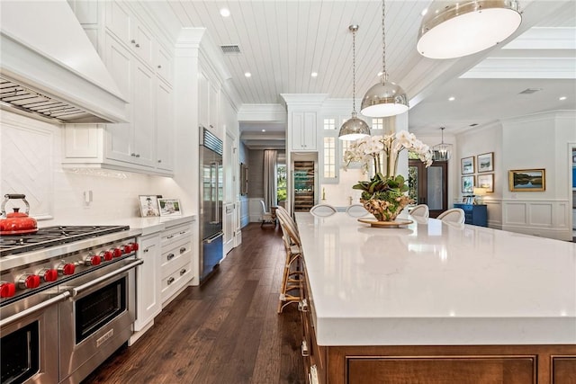 kitchen featuring a large island, a breakfast bar area, premium range hood, hanging light fixtures, and high quality appliances