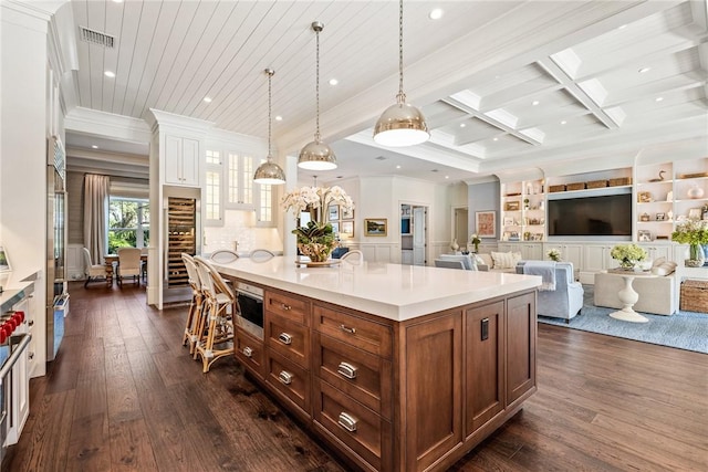 kitchen with pendant lighting, ornamental molding, coffered ceiling, and a kitchen island with sink