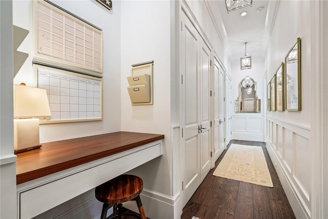 interior space with dark hardwood / wood-style flooring, built in desk, and ornamental molding