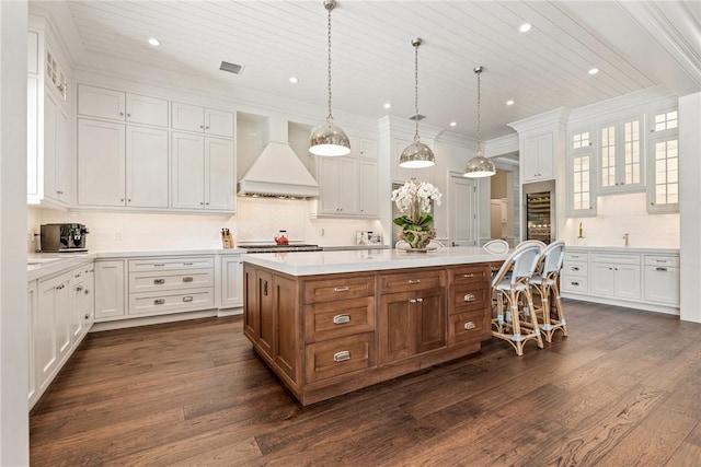 kitchen featuring a center island, custom range hood, white cabinets, dark hardwood / wood-style flooring, and decorative light fixtures