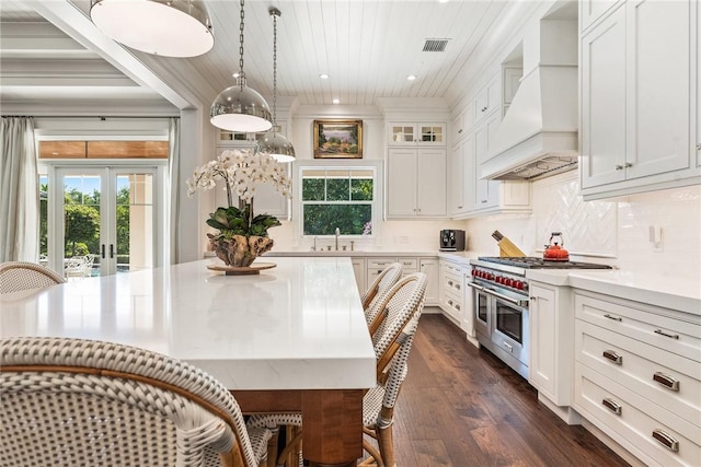 kitchen featuring sink, double oven range, hanging light fixtures, custom range hood, and white cabinets