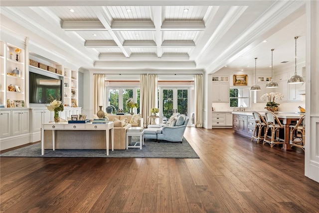 living room with sink, dark wood-type flooring, coffered ceiling, ornamental molding, and beamed ceiling