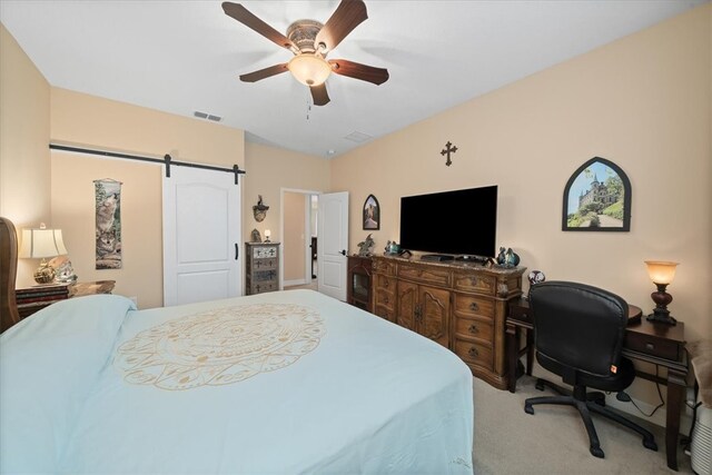 bedroom featuring a barn door, ceiling fan, and light carpet