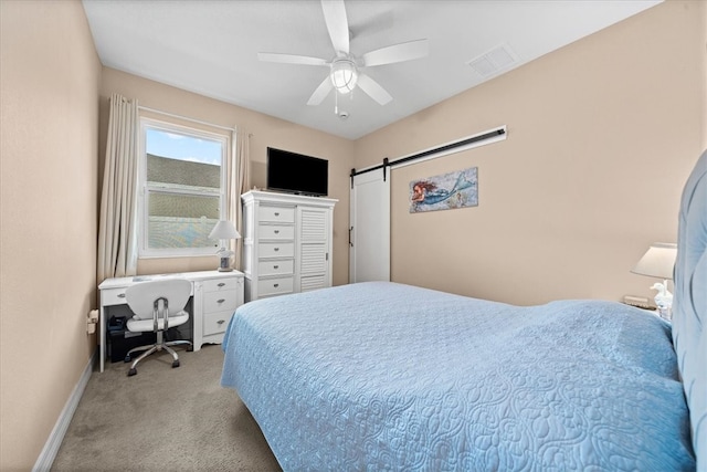 carpeted bedroom featuring a barn door and ceiling fan