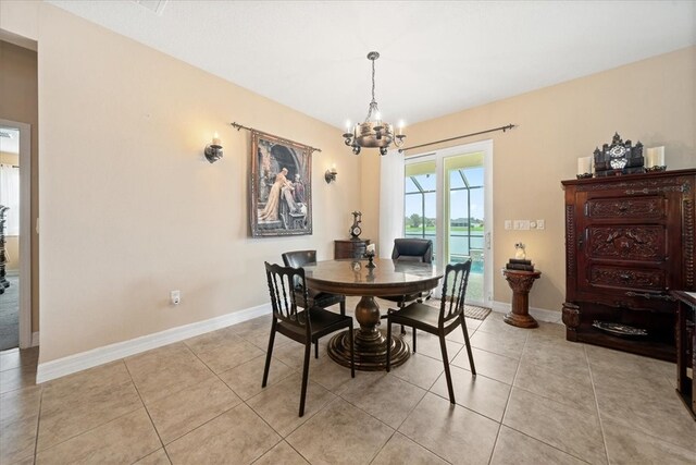 dining room featuring light tile patterned floors, a water view, and a notable chandelier