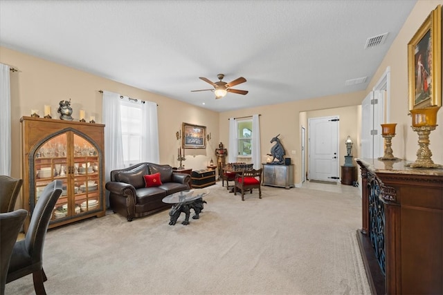 living room with ceiling fan, light colored carpet, and a healthy amount of sunlight