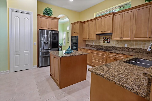kitchen featuring a center island, light tile patterned floors, decorative backsplash, a sink, and black appliances
